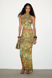 Model in the Soline Skirt, a low-rise asymmetric maxi skirt in animal and peacock print with macramé seams, worn with its matching top