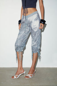 Model wearing the Muse Capri, low-rise slim capri pants with a custom face print and drawstring hems